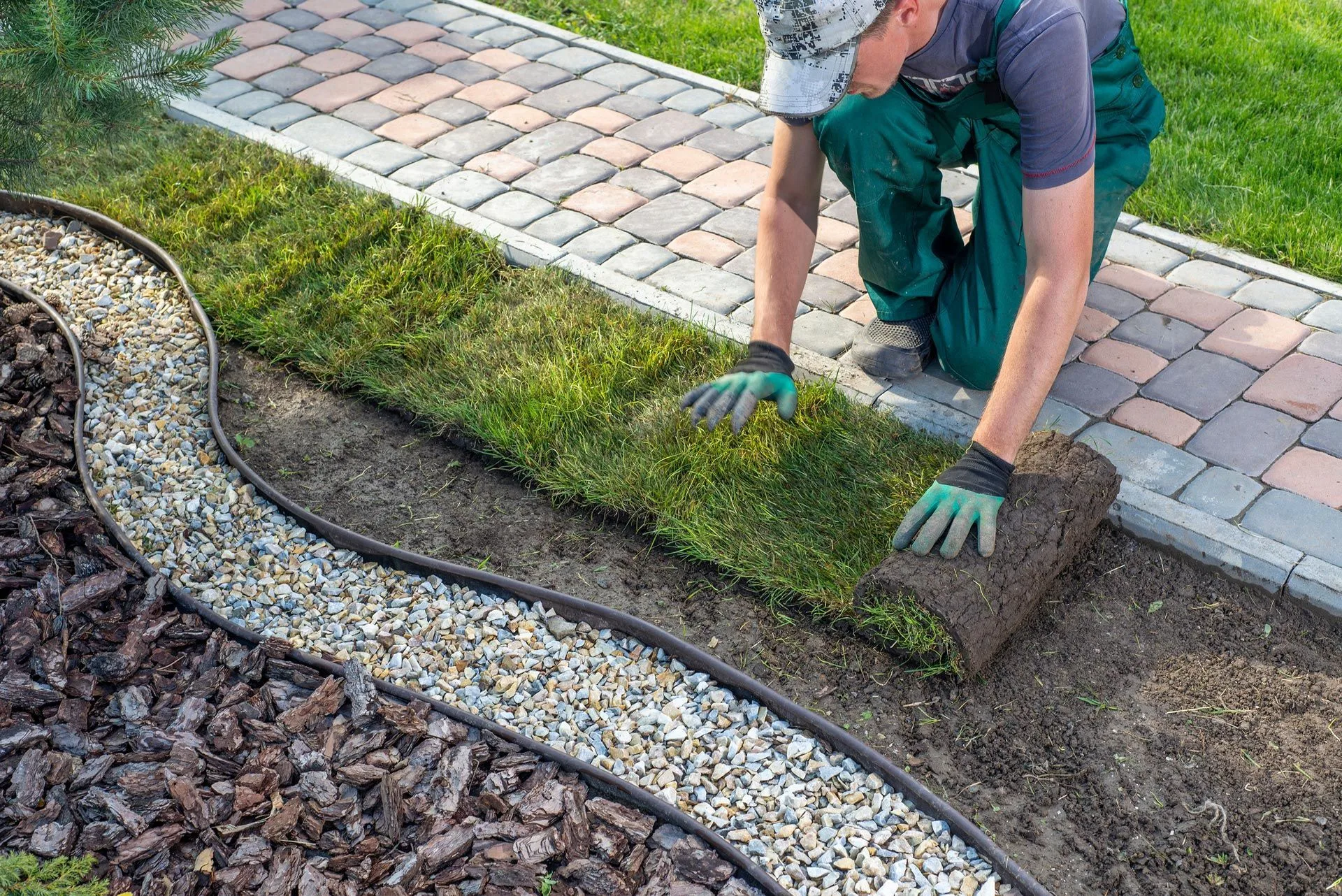 A landscaper is applying turf rolls.